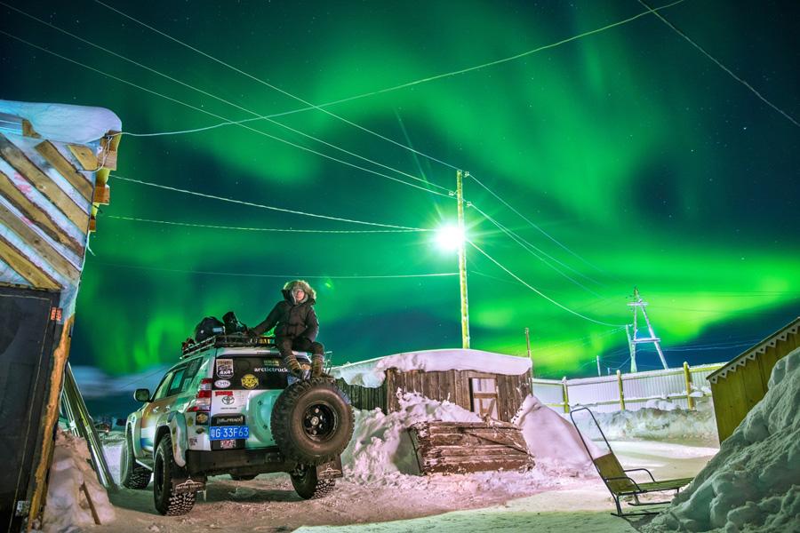 Une photo de Wu Yu, explorateur chinois, assis au sommet de son Toyota Landcruiser modifié, les lumières boréales scintillant au-dessus de lui, après avoir conduit sur 8 000 kilomètres depuis la mer de Chine méridionale jusqu'à l'océan Arctique.